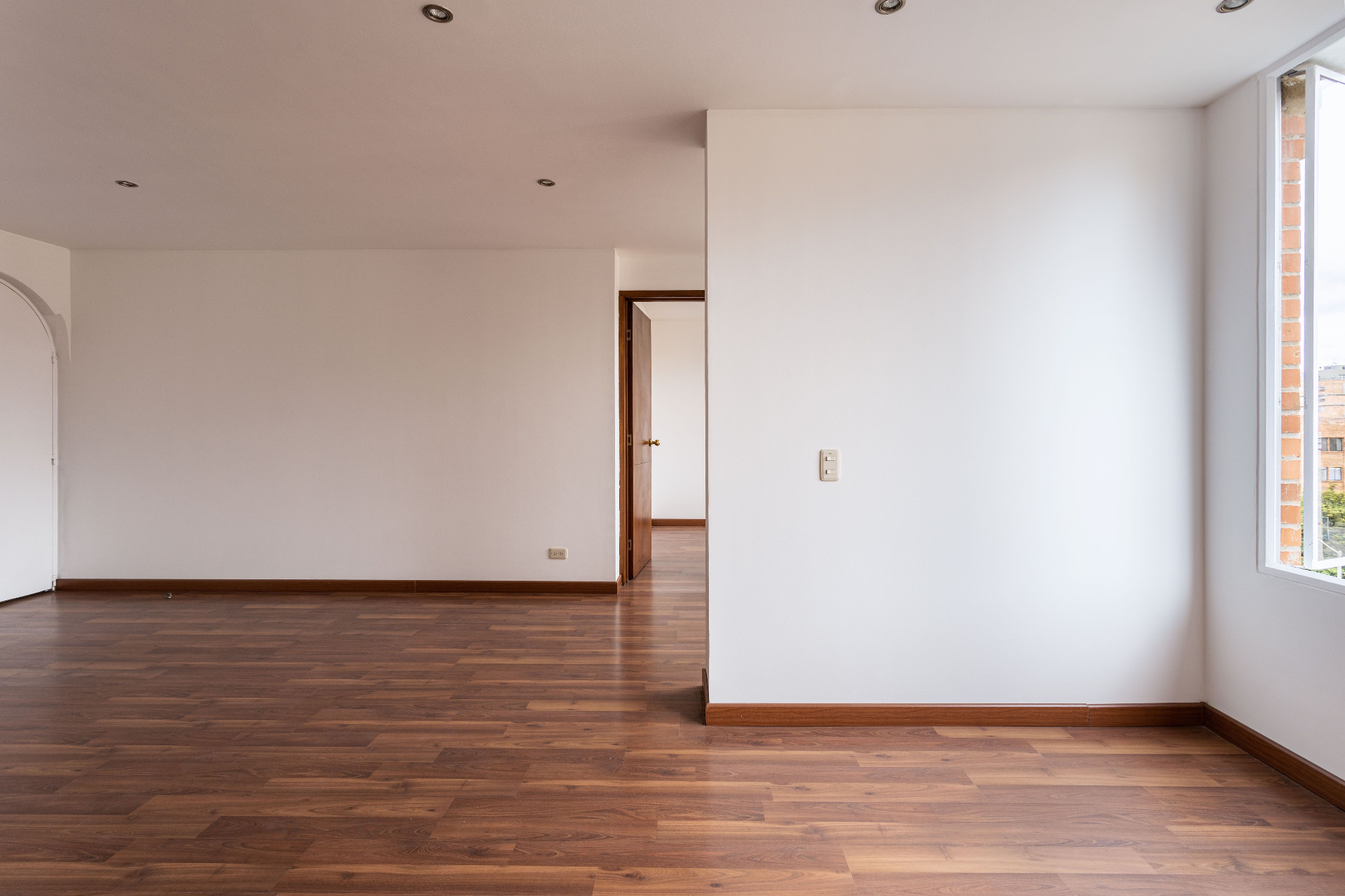 Sala remodelada com pavimento em madeira e paredes renovadas